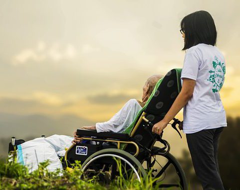 עובד זר מסיע זקן כסא גלגלים